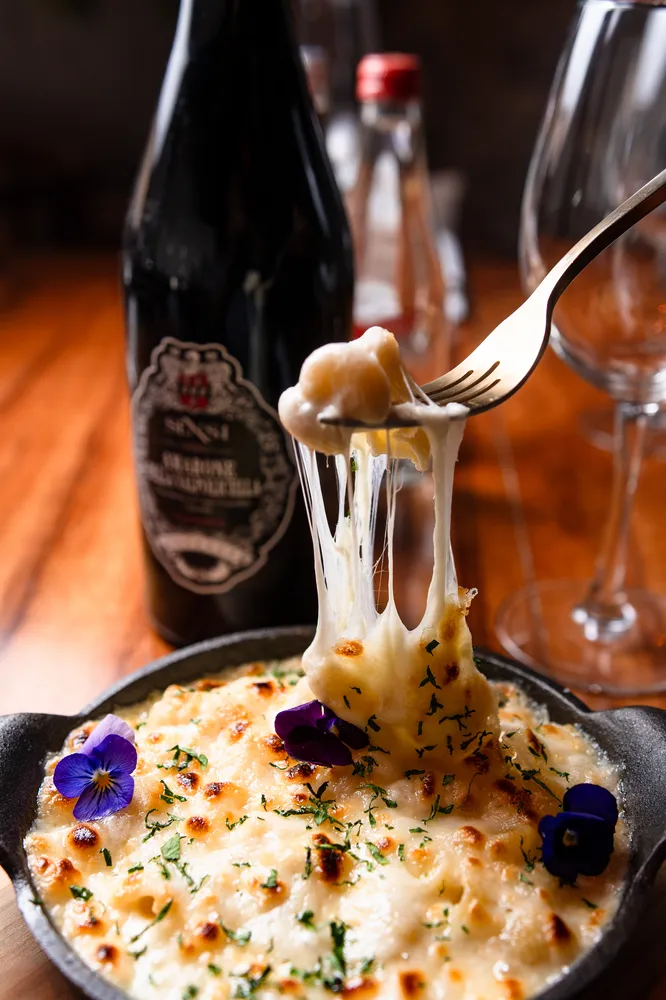 Pasta gratinada al horno con queso fundido y vino en Rosatto, restaurante mediterráneo en Acapulco.